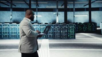 Server room system administrator using laptop to do infrastructure AI machine learning automatization. IT expert in high tech data center doing maintenance using artificial intelligence, camera A video