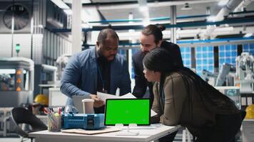 Multiethnic energy consultants coordinating production line next to chroma key, taking quality control measures in a solar power high tech facility. Corporate oversight and execution. Camera B. video
