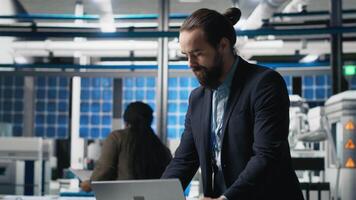 Executive manager in suit conducting an inspection in a solar panel factory, symbolizing modern manufacturing and efficiency in alternative energy. Production planning and technology. Camera A. video