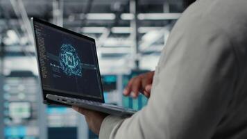 Close up of server hub admin using laptop to do infrastructure AI machine learning automatization. Data center programmer doing maintenance using artificial intelligence, camera B video