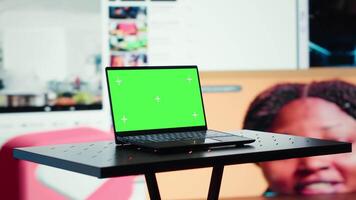 Green screen laptop in front of wall displaying online videos on social media feed. Mockup notebook and digital interface showing internet engagement and multimedia entertainment