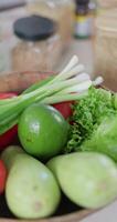 Vertical slow-motion footage of plate with broccoli, green onion, red radish, lettuce, pomegranate, tomatoes and avocado, next to jars of spices and cereals video