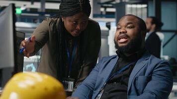 Black team of engineers technicians share ideas in a solar panel factory, reviewing blueprints and sharing ideas to enhance renewable energy production and sustainable innovation. Camera A. video