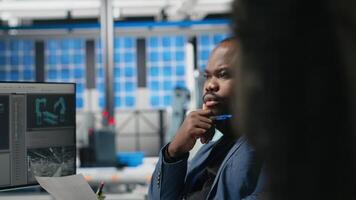 Master engineer reviewing production line metrics on papers, managing factory activity in a solar panel facility to ensure effective quality control to renewable energy tech. Camera A. video
