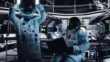Team of astronauts running data analysis on laptop before stepping out outside space station. Teamworking cosmonaut verifying mission parameters on notebook after landing on planet, camera A video
