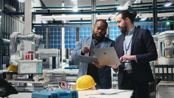 Team of diverse analysts consultants reviewing data and checklists in a high tech solar panel plant, ensuring manufacturing process meets sustainable energy and innovation standards. Camera B. video