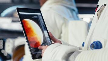 Close up of astronaut using tablet to check logs after completing red planet surface mission. Cosmonaut leaving Mars, updating flight log on device to return home, camera B video