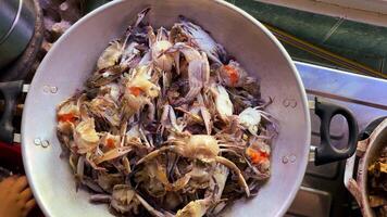 A woman hand placing soft shell crabs or kepiting soka into a wok for cooking. Traditional Indonesian seafood dish using molted crabs with edible shells video
