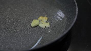 Fried sliced garlic and boiling food oil in the black pan. video
