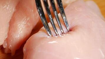 Cooking chicken by tenderizing raw meat with a fork video