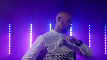 Live DJ performance of emotional energetic bald man with mixer controller. Composing new mix, dancing, performing on concert musician stage with lights. Party, music festival show concert. Slow motion video