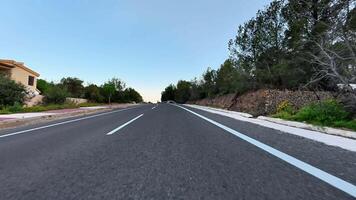 An exceptionally captivating view of a smooth asphalt road gracefully bordered by lush greenery under a clear blue sky photo