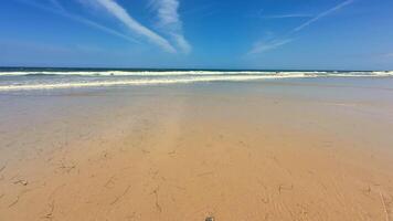 A tranquil beach scene vividly showcasing gentle waves lapping against the shore and a beautiful blue sky overhead photo