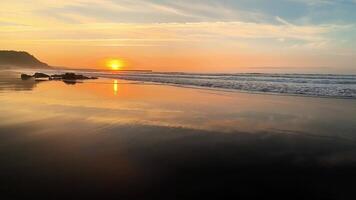The breathtaking sunset is beautifully reflecting on the calm, tranquil ocean waters accompanied by gentle waves photo