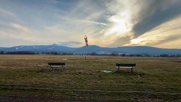 A tranquil and picturesque scene showcasing benches, expansive open fields, and majestic mountains under a stunning sky photo