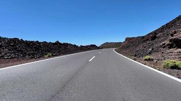 A picturesque winding road meanders through stunning volcanic terrain beneath a beautifully clear blue sky photo