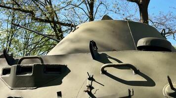 The intricately detailed view of a tanks hull, which is surrounded by lush greenery, emphasizes military history photo