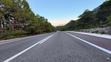 A beautiful and picturesque winding road encircled by lush greenery and majestic mountains as the sun sets photo