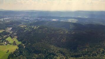 This aerial view highlights vibrant green forests and rolling hills, beautifully framed by a hazy sky photo