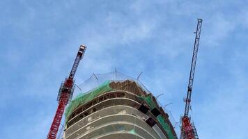 Capturing the ongoing construction of a highrise building, featuring cranes and scaffolding all around it photo