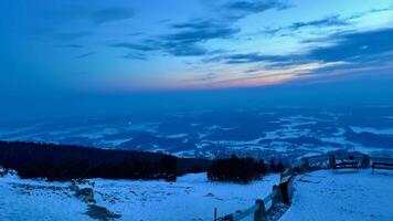 Evening view of snow-capped mountains and bright sky at sunset from an observation deck on top of a mountain. High quality 4k footage photo