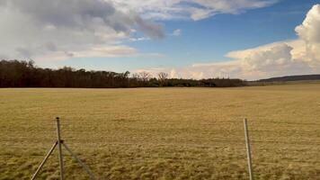 A serene and peaceful view showcasing expansive fields under a bright blue sky dotted with fluffy, scattered clouds photo