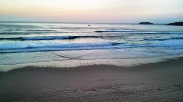 A serene beach scene at sunset showcasing gentle waves caressing the shore and a sky bursting with beautiful colors photo