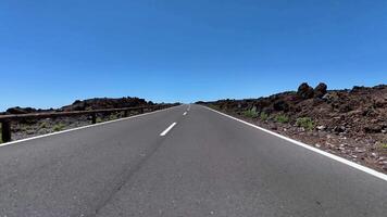 A mesmerizing view of a long highway cutting through a unique volcanic terrain under a clear blue sky. photo