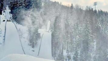 A truly stunning snowy landscape that features an impressive ski jump, surrounded by tall, majestic evergreen trees photo