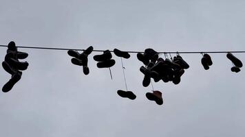 An artistic and creative display of various shoes hanging on a wire, beautifully set against a cloudy backdrop photo