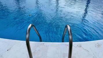 Experience a serene pool view that features elegant palm trees, an urban backdrop, and calm, inviting blue waters photo