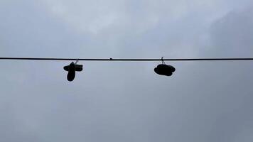 A unique pair of shoes hangs on a power line against a dramatic cloudy sky, capturing urban culture and community photo