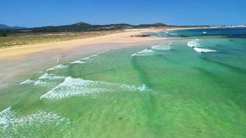 This aerial photograph captures turquoise waves breaking on a calm beach, creating a picturesque view photo