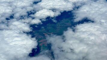 A breathtaking aerial view of a vast and lush landscape that is partially hidden by soft, fluffy white clouds photo