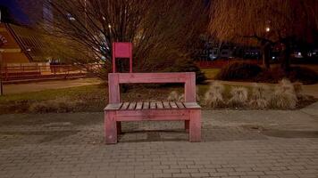 A vibrant pink bench shines brightly illuminated at night, beautifully showcasing urban design in a lively park photo