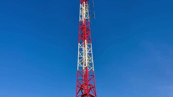 A tall communication tower featuring distinct red and white sections, beautifully set against a clear blue sky photo