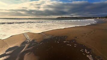 A peaceful and serene beach view showcases gentle waves, footprints on the golden sand, under a cloudy sky photo