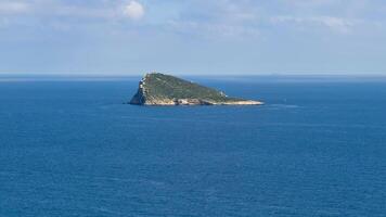A stunning and beautiful island gracefully rising from the tranquil and serene blue waters beneath a clear sky photo