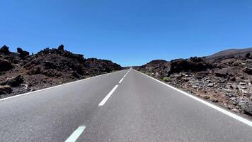 The stunning view of a straight road through volcanic rock formations under a clear blue sky is captivating photo