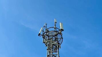 A tall communication tower with antennas looms against a blue sky, symbolizing modern technology and connectivity photo