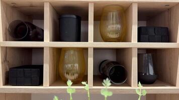 The beautiful display features a variety of elegantly arranged glasses and containers neatly placed on a wooden shelf photo