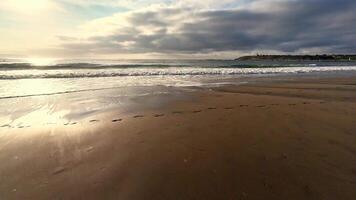 A tranquil beach scene featuring soft waves and footsteps in the sand, perfect for relaxation themes. photo