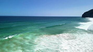 A breathtakingly beautiful view of a stunning beach featuring azure waves and people joyfully enjoying the warm sun photo