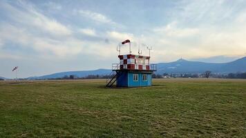 A vibrant wind observation tower is surrounded by lush greenery and stunning mountains beneath a cloudy sky photo