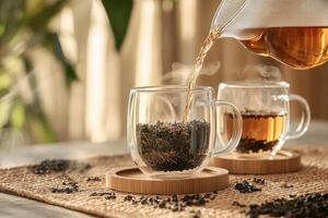 Tea being poured into glass mugs with loose leaf tea photo