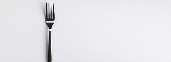 A single silver fork rests on a white background photo
