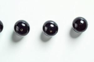 Three dark glistening jabuticabas arranged in a row photo