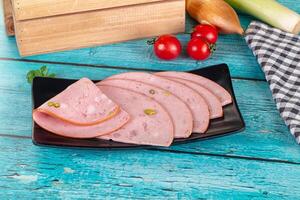 Sliced ham on a black plate with vegetables and a wooden box photo