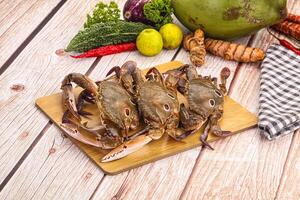 A wooden table with crabs, vegetables and a towel photo