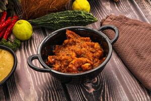 A bowl of food sitting on a table next to a bowl of sauce photo